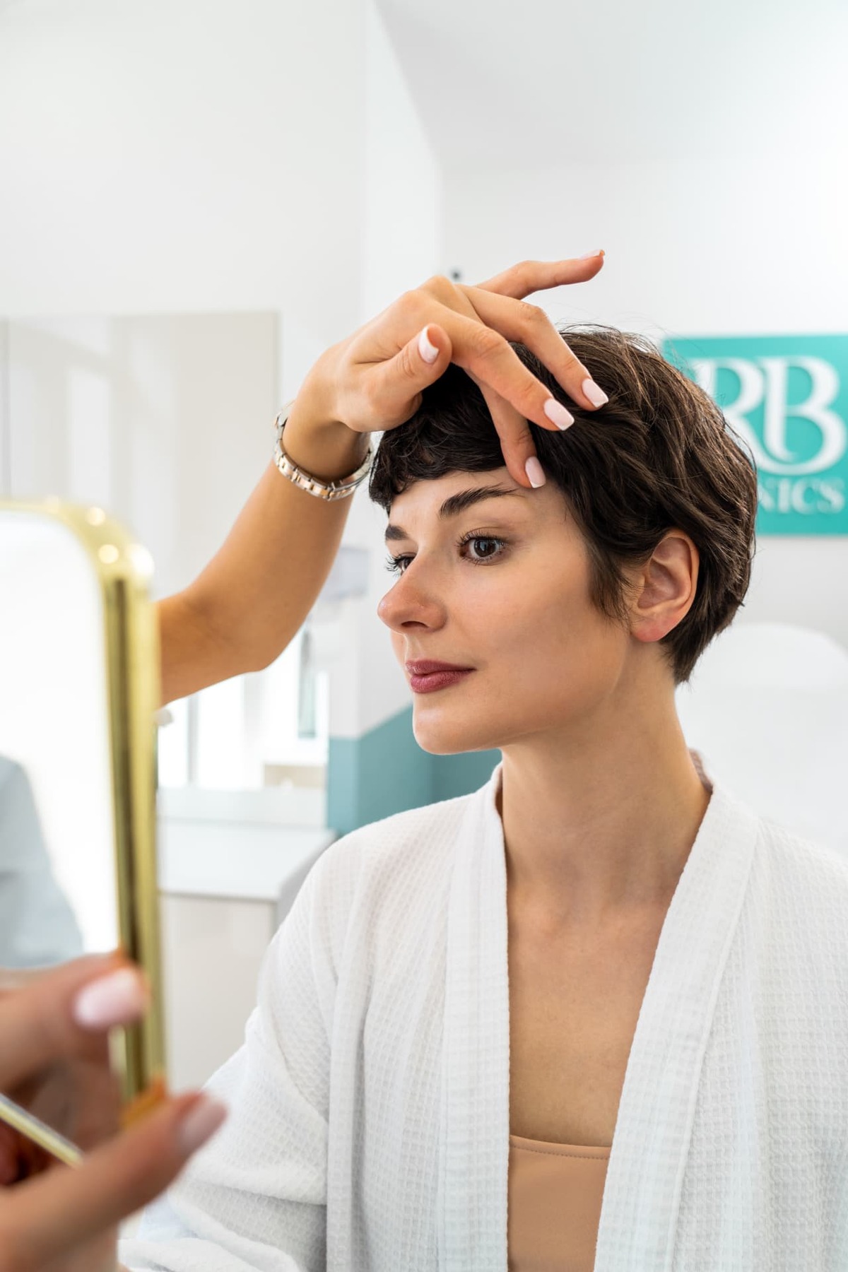 Specialist van RB Clinics beoordeelt de huid van het gezicht terwijl de cliënte meekijkt in de spiegel