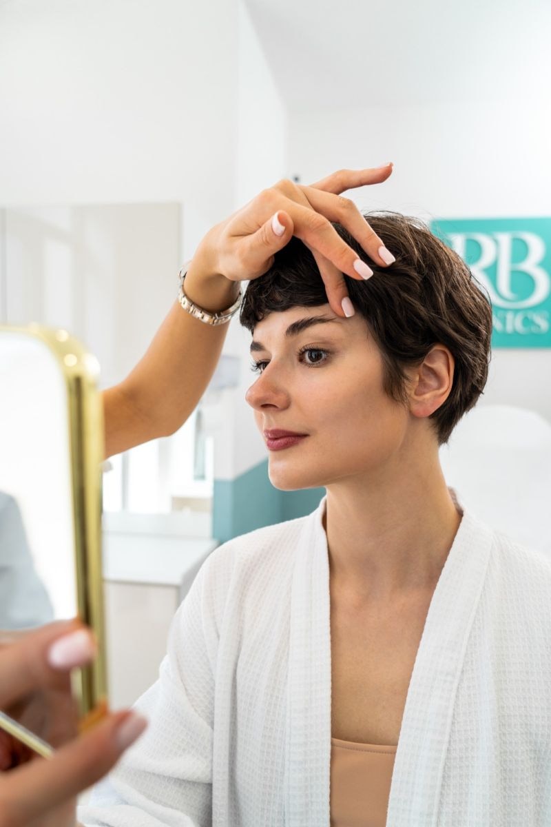 Specialist bekijkt de huid van een cliënte tijdens een huidbehandeling bij RB Clinics